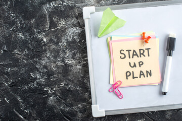 Wall Mural - top view start up plan note on sticker inside open copybook on gray background school lesson student