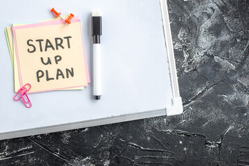 Wall Mural - top view start up plan note on sticker inside open copybook on gray background school lesson student