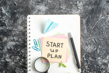 Wall Mural - top view start up plan note on sticker with pen and magnifier on a gray background lesson student pa