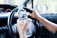 Asian Woman Driver Hold Cold Water For Drink In Car, Dangerous And Risk An Accident.