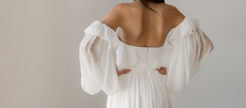 Gorgeous long wedding backless dress. Bride in the shoulderless white wedding dress with fancy sleeves
