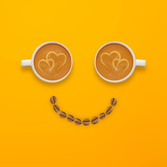 Smile look made from two cups of coffee and coffee beans on yellow background