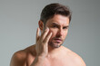 © Volodymyr - Close up portrait of man 40s applying cream on face. Handsome serious man enjoy fresh perfect skin, applying cream. Portrait of beauty man with cosmetic cream on skin. Facial treatment. male beauty.