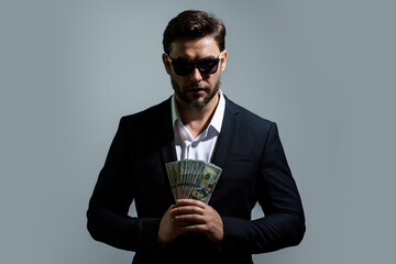 Portrait business man holding cash dollar bills over gray background. Big luck, banner. Dollar cash money concept. Rejoices to win cash. Man hold cash money. Financial luck and success.