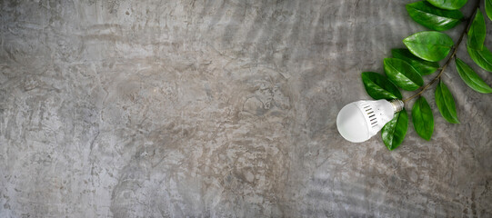 Wall Mural - led light bulb on a background of green leaves, as a symbol of green energy, energy saving and envir
