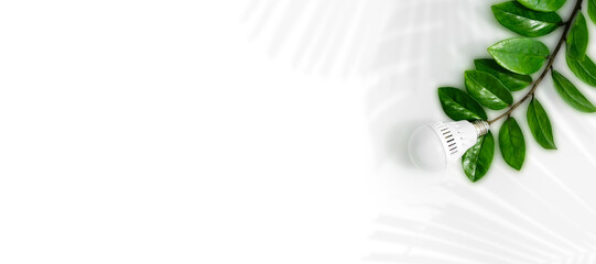 Wall Mural - led light bulb on a background of green leaves, as a symbol of green energy, energy saving and envir
