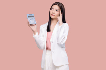 Canvas Print - Young Asian woman feel confuse hold in hands calculator isolated on pastel pink background studio portrait.