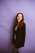 © contrastwerkstatt - Radiant Redhead Woman Standing in Front of Purple Background with Joyful Laughter