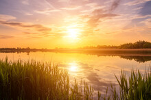 Scenic View Of Beautiful Sunset Or Sunrise Above The Pond Or Lake At Spring Or Early Summer Evening.