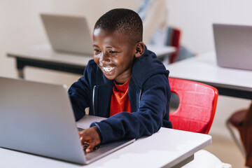 Wall Mural - Building tech skills for a better tomorrow: Young boy enjoys coding on a laptop in a digital literacy class