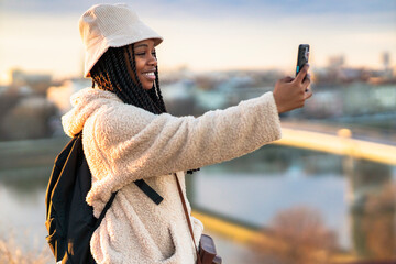 Beautiful tourist taking a picture with her phone after sites seeing all day in a new city, she's a student in a new city for winter holiday break