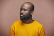 © pressmaster - Portrait of African American man in yellow shirt looking away with sad expression on brown background