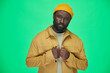 © pressmaster - Portrait of African American man in yellow hat and jacket looking at camera on green background