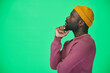 © pressmaster - Side view of African American man in yellow hat loooking away with pensive expression against green background