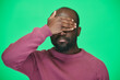 © pressmaster - Portrait of African American man covering his eyes with hand standing against green background