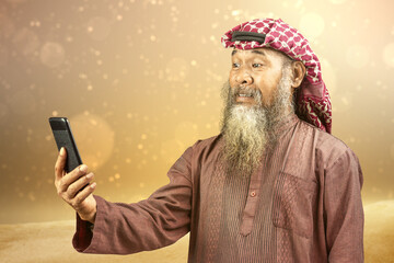 Poster - Muslim man with a beard wearing keffiyeh with agal using mobile phone