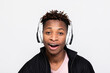 Stylish young man showing different emotions posing in studio isolated over white background in new last series headphones earphones opening mouth showing beautiful white teeth.