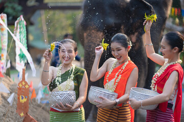 Wall Mural - Tourist Asian people wearing traditional Thai dresses are happy to play splashing water during Songkran festival for travel a funny happy holiday in popular culture Thailand.