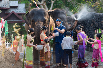 Wall Mural - Tourist Asian people wearing traditional Thai dresses are happy to play splashing water during Songkran festival for travel a funny happy holiday in popular culture Thailand.