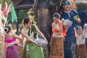 Wall Mural - Tourist Asian people wearing traditional Thai dresses are happy to play splashing water during Songkran festival for travel a funny happy holiday in popular culture Thailand.