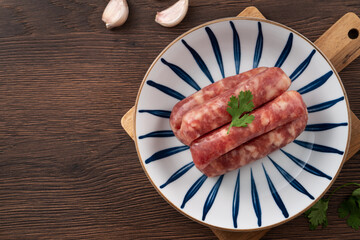 Wall Mural - Raw Taiwanese sausage in garlic flavor in a plate on wooden table background.