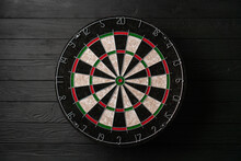 New Classic Professional Sisal Dart Board On Black Wooden Background. Close Up.