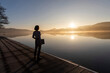 © Westend61 - Freelancer standing with laptop looking at lake