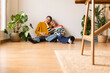 © Westend61 - Smiling mother and daughter sitting on hardwood floor at home