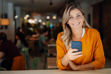 Happy Woman With Mobile Phone In Cafe