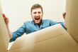 © Westend61 - Young man screaming and looking inside cardboard box