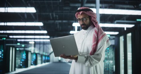 Wall Mural - Portrait of a Middle Eastern IT System Engineer Wearing Traditional White Robe, Using Laptop Computer in a Modern Technological Server Farm Facility. Arab Artificial Intelligence Expert at Work