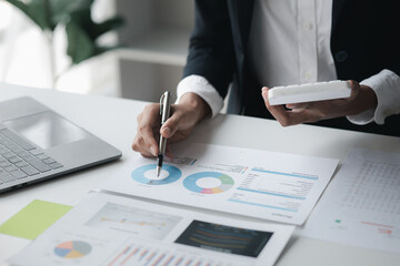 A female financier is reviewing company financial documents, monthly financial statement summary from the finance department. The concept of managing the company's finances for accuracy and growth.