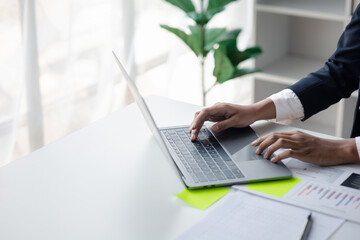 A business women working in a private room, He is typing on a laptop keyboard, He uses a messenger to chat with a partner. Concept of using technology in communication.