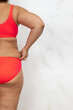 © Юля Бурмистрова - Photo of half of female cellulite body with back, free copy space, white background. Bare woman in red underwear pinch fat folds by hands. Overweight people, weight loss, self acceptance.