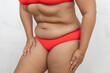 © Юля Бурмистрова - Unrecognizable overweight, fat woman in red lingerie leaning forward in pain, holding thighs and hips on white studio background. Pain in articulations, joints, back. Healthcare and medicine problem