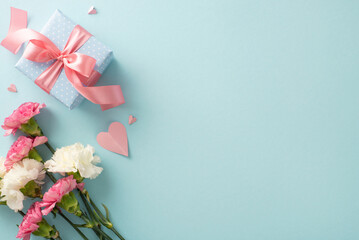 Wall Mural - Mother's Day appreciation concept. Top view flat lay photo of beautiful present boxes with pink ribbons, carnation flowers, and pink paper hearts on pastel blue background with blank space