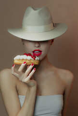 Portrait of beautiful young happy girl eating cake, close up. Chocolate background. Smiling girl playing with dessert.