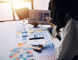 Close up ux developer and ui designer brainstorming about mobile app interface wireframe design on table with customer breif and color code at modern office.Creative digital development agency