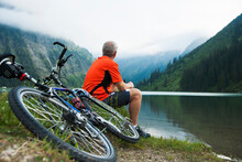 Mature Man Sitting By Lake With Mountain Bike, Vilsalpsee, Tannheim Valley, Tyrol, Austria