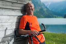 Mature Man Leaning Against Wooden Building With Mountain Bike, Vilsalpsee, Tannheim Valley, Tyrol, Austria