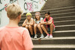 © Designpics - Backview of boy approaching girls sitting on stairs outdoors, Germany