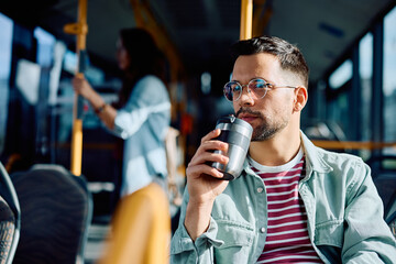 Wall Mural - Pensive man drinks takeaway coffee while riding in bus.