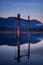 Swing Set On Wooden Posts With Swing And Rope Swing In The Tranquil Water Of Sproat Lake At Sunrise, Vancouver Island, BC, Canada; Vancouver Island, British Columbia, Canada