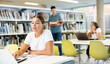 © JackF - Focused European casual female writing in notepad and using laptop in the library