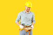 Male carpenter sharpening wooden plank with file on yellow background