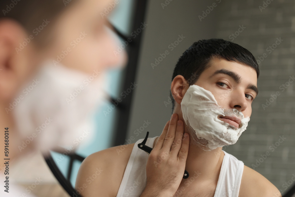 Young man shaving in bathroom