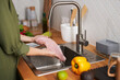 Closeup of young woman washing chicken breast meat in tap water, copy space