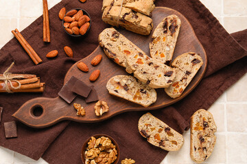 Wall Mural - Composition with tasty biscotti cookies, nuts, cinnamon and chocolate on light tile background