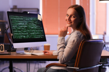 Female programmer working with computer in office at night
