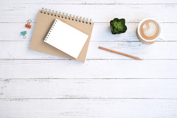 Wall Mural - Flat lay,  Blank notepad and coffee cup with green plant on wooden white table desk background ,Top view with copy space